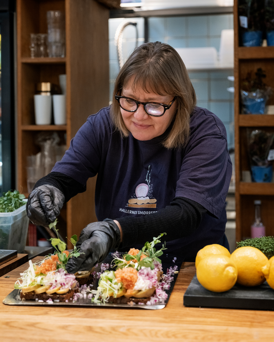 Højtbelagt smørrebrød anrettes nænsomt på trædisken